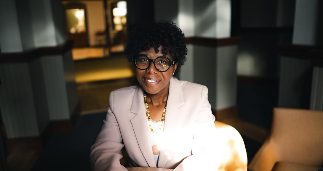 Robin Sundaramoorthy sits on a yellow sofa and smiles at the camera.